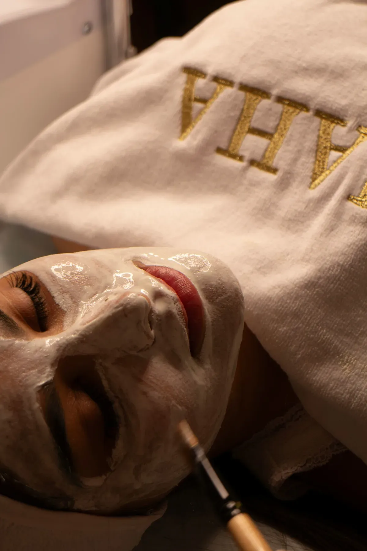 Femme recevant un soin du visage avec un pinceau dans une ambiance douce