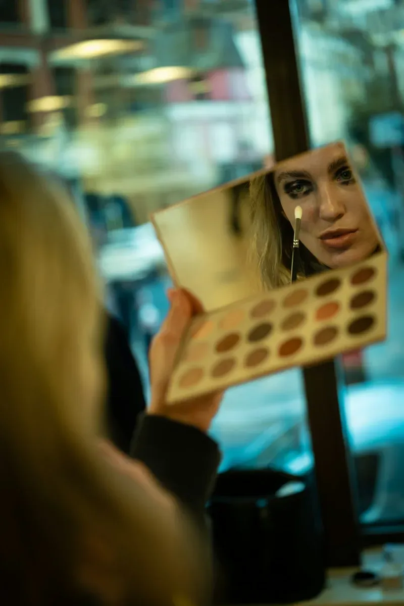 Femme appliquant un maquillage dramatique des yeux devant un miroir